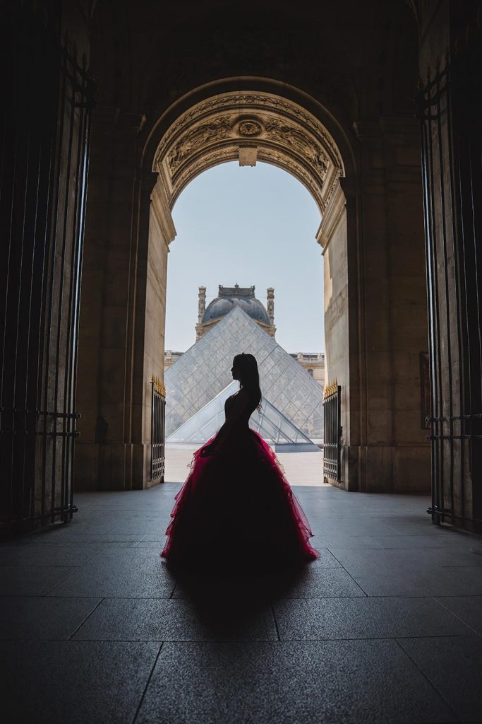 Silueta de quinceañera con vestido rojo frente a la pirámide del Louvre en París / Silhouette of a quinceañera in a red dress in front of the Louvre pyramid in Paris